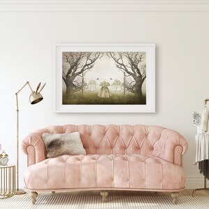 May include: A pink tufted sofa with a brown throw pillow in front of a white wall with a framed print of a foggy forest scene with three dresses hanging on a clothesline.