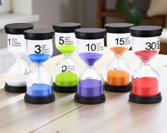 Op de afbeelding: Zes zandlopers met zwarte doppen en bases. Elke zandloper heeft gekleurd zand: wit, blauw, groen, paars, oranje en rood. De zandlopers zijn gemarkeerd met de tijd in minuten: 1, 3, 5, 10, 15 en 30.