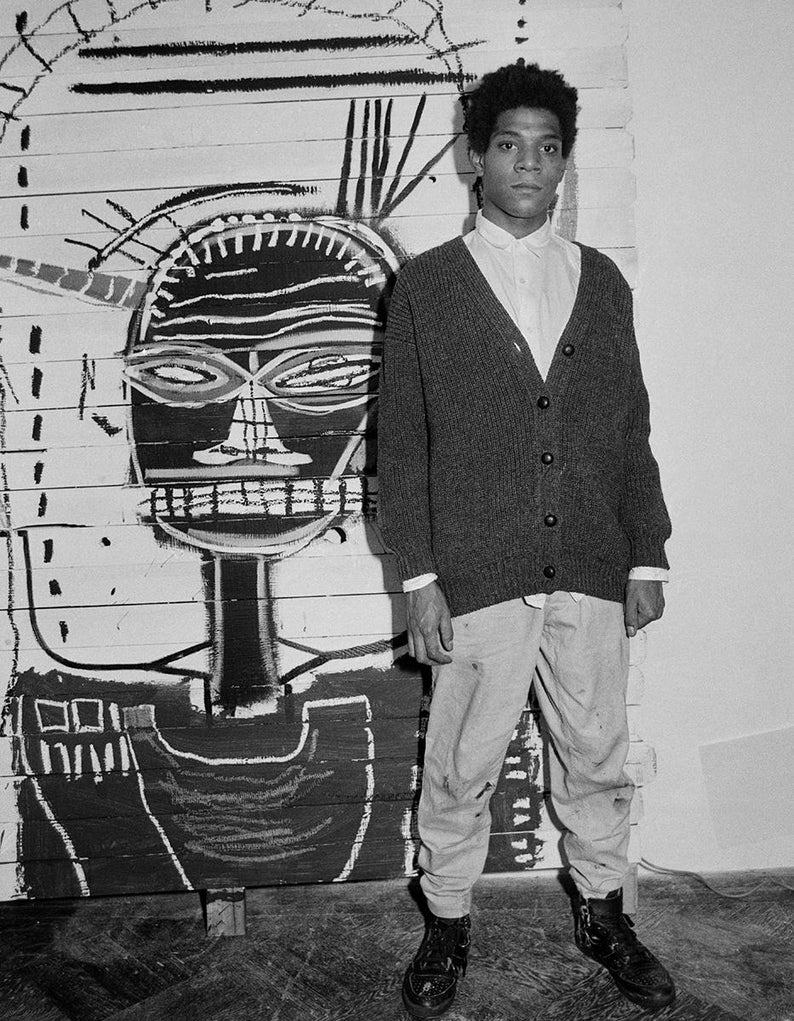 K&ouml;nnte beinhalten: Ein Schwarzwei&szlig;foto eines Mannes, der vor einem gro&szlig;en Gem&auml;lde steht. Das Gem&auml;lde ist ein abstraktes Schwarzwei&szlig;portr&auml;t mit einem gro&szlig;en, stilisierten Gesicht. Der Mann tr&auml;gt einen dunklen Cardigan, eine helle Hose und dunkle Schuhe.