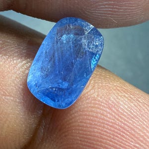 Puede incluir: Una gema azul brillante, de forma rectangular con bordes redondeados. La superficie est&aacute; facetada, captando la luz y revelando patrones internos. El color es un azul profundo y saturado.