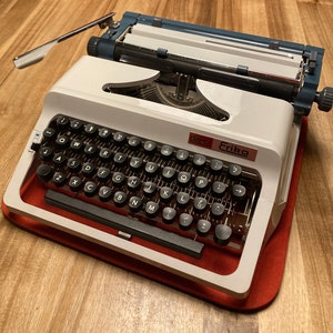 Erika Daro Model 34 Typewriter (1977) – Made in East Germany – QWERTY – 10 CPI Typeface – Cream and Blue – With Case and Brushes – Working