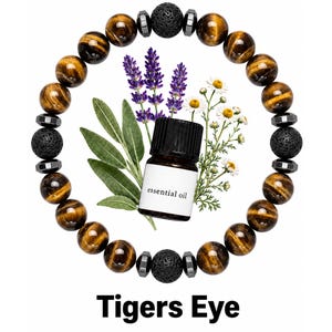 May include: A circular beaded bracelet featuring brown and gold tiger eye stones, black porous lava beads, and small metallic spacers. In the center, a small brown glass bottle labeled essential oil is surrounded by lavender and chamomile sprigs.