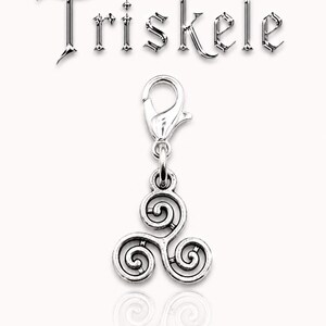May include: A silver-colored Triskele charm with a lobster clasp. The charm features a three-spiral design, and the word "Triskele" is displayed above the charm in a metallic font. The charm is displayed on a white background.