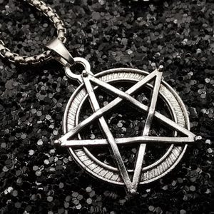 May include: A silver-colored pendant necklace featuring a pentagram within a circle. The pendant hangs from a chain with a textured, linked design. The background is a dark, glittery surface.