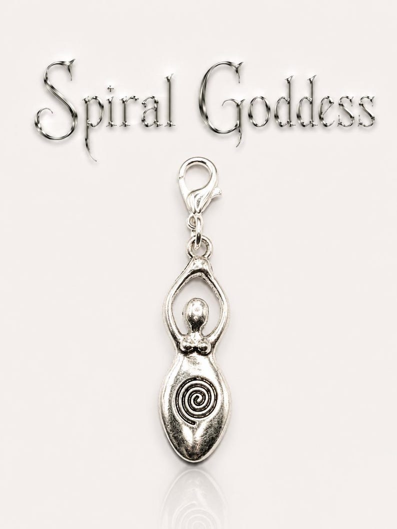 May include: A silver-colored charm with a goddess figure and a spiral design. The charm is attached to a clasp and has the words "Spiral Goddess" above it. The charm is likely made of metal and is on a white background.
