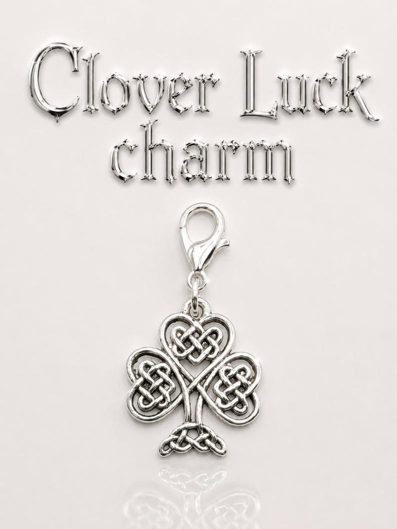 May include: A silver-colored clover charm with a Celtic knot design. The charm is attached to a clasp and is displayed against a white background. The words "Clover Luck charm" are written above the charm.