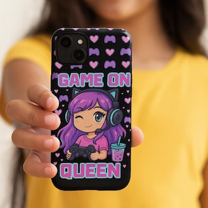May include: Black phone case with a cartoon gamer girl design. The case features the text "GAME ON QUEEN" in teal and pink. The design includes hearts, game controllers, and a character with purple hair and headphones.