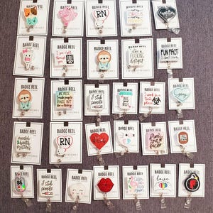 Peut inclure: Une collection de 25 porte-badges colorés avec différents motifs et dictons. Les porte-badges sont affichés sur une surface grise. Certains des motifs incluent un paresseux, un cœur, une dent, un flamant rose, un arc-en-ciel et une coiffe d'infirmière. Les dictons incluent "Je pique les gens", "Prenez vos médicaments", "Calmez-vous", "La santé mentale compte", et "Ce n'est pas mon cirque, ce ne sont pas mes singes".