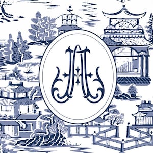 Op de afbeelding: Een blauw en wit toile de Jouy-patroon met een landschap met pagodes, bruggen en bomen. Een witte ovaal in het midden bevat de verweven letters "JA" in een donkerblauw, decoratief lettertype. Het ontwerp heeft een klassieke, elegante uitstraling.