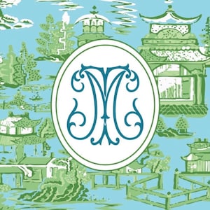 Op de afbeelding: Een lichtblauw en groen Chinoiserie-patroon met pagodes, bomen en bruggen. Een ovaal embleem met een turquoise "M"-monogram staat centraal. Het ontwerp doet denken aan traditionele Aziatische kunst.
