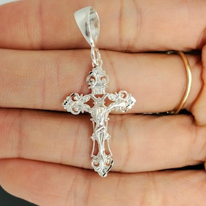 May include: Silver filigree crucifix pendant with a detailed depiction of Jesus Christ on the cross. The pendant features a bail for attaching to a chain.