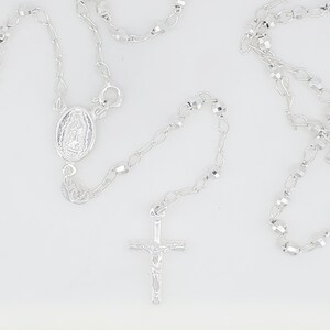 Pode incluir: Colar de ros&aacute;rio de prata com uma cruz de prata e um pingente oval de prata com uma imagem religiosa.