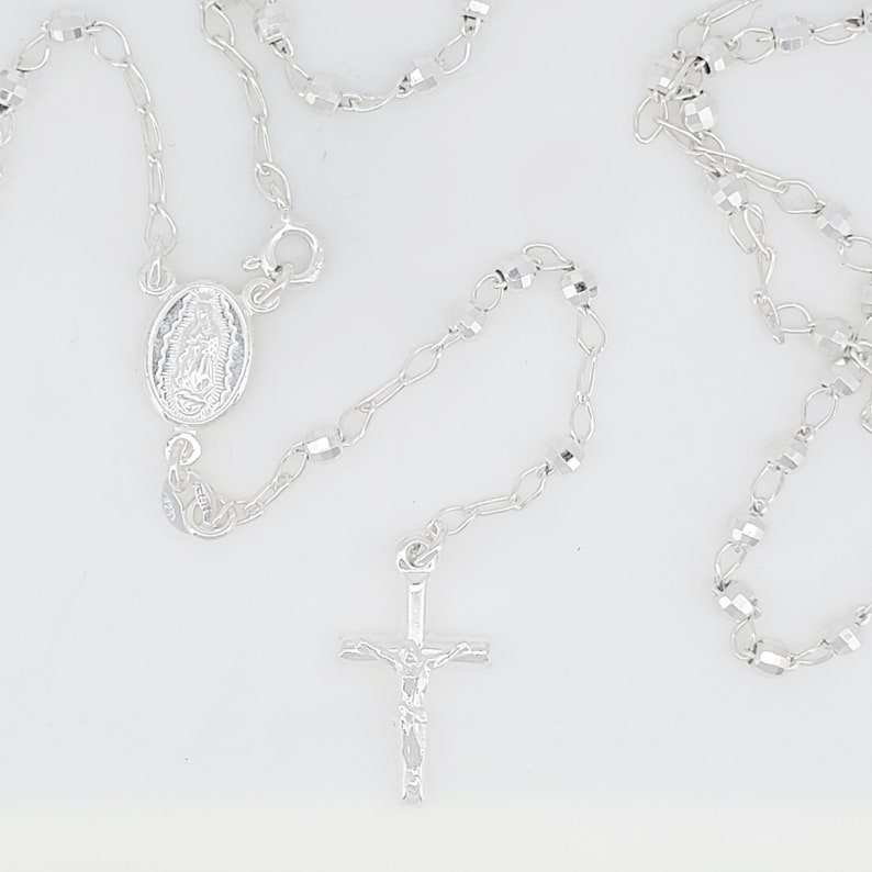 Pode incluir: Colar de ros&aacute;rio de prata com uma cruz de prata e um pingente oval de prata com uma imagem religiosa.