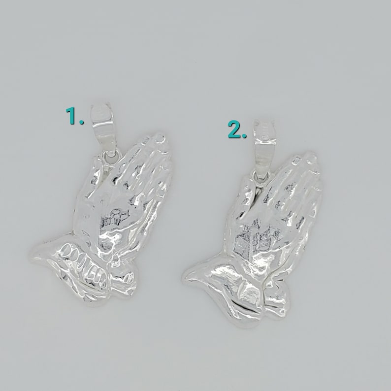 May include: Two silver praying hands charms with a loop for attaching to a necklace or bracelet.