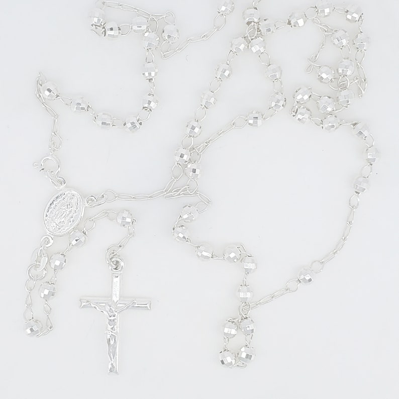 Pode incluir: Um ros&aacute;rio de prata com um crucifixo de prata e uma medalha de prata da Virgem Maria.