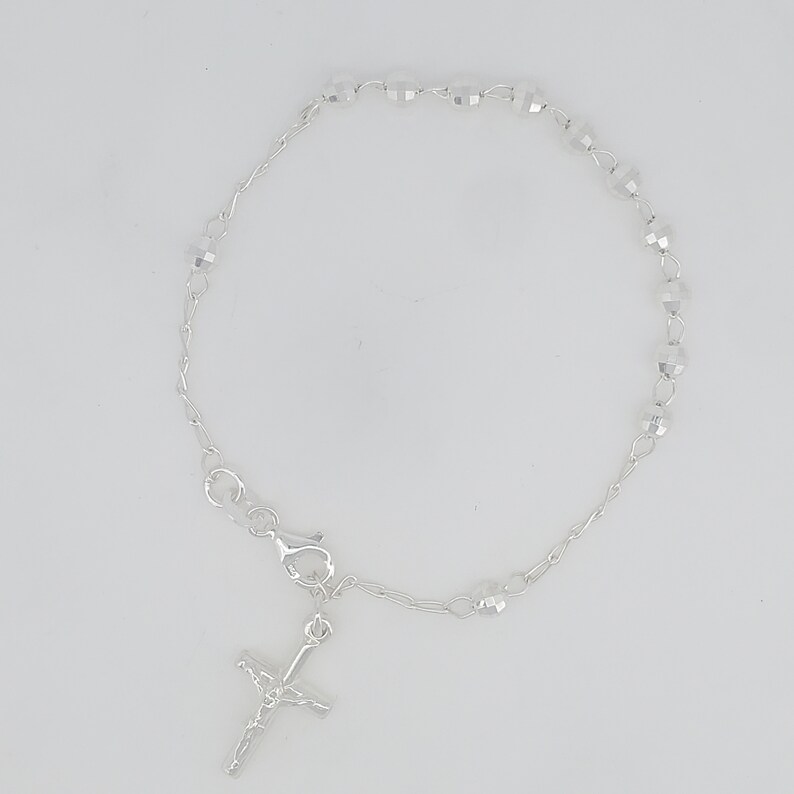 May include: A silver bracelet with a small silver cross charm and clear crystal beads.