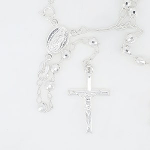Pode incluir: Colar de ros&aacute;rio de prata com um crucifixo de prata e um pingente oval de prata com uma imagem religiosa.