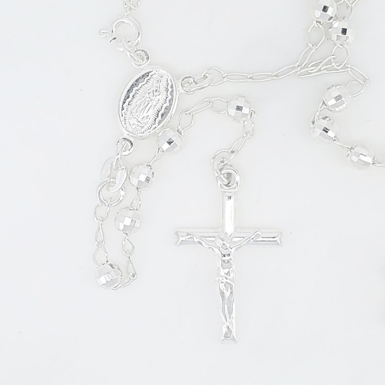 Pode incluir: Colar de ros&aacute;rio de prata com um crucifixo de prata e um pingente oval de prata com uma imagem religiosa.
