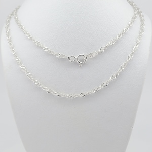 May include: A silver rope chain necklace with a lobster clasp. The chain is double-stranded and has a delicate, twisted design.