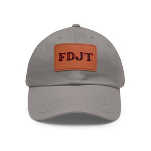 May include: A grey baseball cap with a brown leather patch that says "FDJT" in red letters.