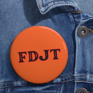Puede incluir: Botón naranja con el texto "FDJT" en negro con contorno rojo.