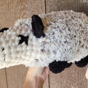 Puede incluir: Un juguete de peluche de zarig&uuml;eya hecho a mano. La zarig&uuml;eya es gris y blanca con orejas, patas y marcas oculares negras. Tiene una nariz y una cola rosas. El juguete de peluche est&aacute; hecho de un material suave y texturizado.