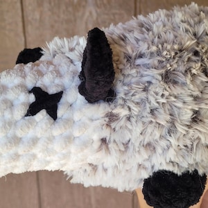Puede incluir: Un juguete de peluche de zarig&uuml;eya hecho a mano. La zarig&uuml;eya es principalmente gris y blanca con detalles en negro para las orejas, los pies y los ojos. La nariz es rosa. Los ojos son cruces negras. La cola es rosa.