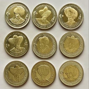 以下が含まれることがあります： ターバンとあごひげをつけた人物の浮き彫りがある金色のコインが9枚。各コインには縁に「OSMANLI PADISAHLARI」という文字が刻まれ、中央には異なるオスマン帝国のスルタンの名前と統治期間が記されています。