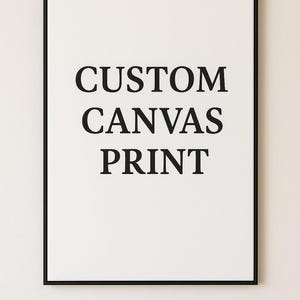 K&ouml;nnte beinhalten: Ein rechteckiger Leinwanddruck mit schwarzem Rahmen und wei&szlig;em Hintergrund, auf dem der schwarze Text CUSTOM CANVAS PRINT zentriert ist. Unter dem Rahmen ist der Text 60 x 90 cm aufgedruckt, der die Ma&szlig;e des Leinwanddrucks angibt.