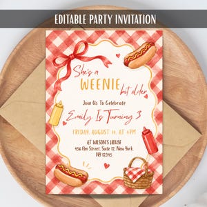 May include: An editable party invitation with a red and white gingham background. The text reads: She's a WEENIE bit older, Join Us To Celebrate Emily Is Turning 3, FRIDAY, AUGUST 14, AT 4PM, AT WILSON'S HOUSE, 456 Elm Street, Suite 12, New York, NY 12345.