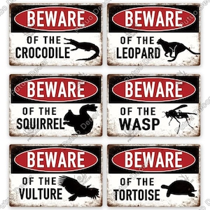 May include: A set of six rectangular metal signs with a distressed, vintage look. Each sign features a red and white oval with the word "BEWARE" and a warning about various animals, including a crocodile, leopard, squirrel, wasp, vulture, and tortoise.