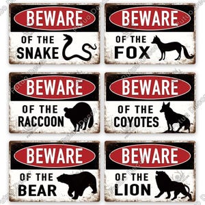 Puede incluir: Seis señales de advertencia de metal de estilo vintage con fondos negro y rojo. Cada señal dice "Cuidado" y presenta una silueta de animal diferente: serpiente, zorro, mapache, coyote, oso y león.