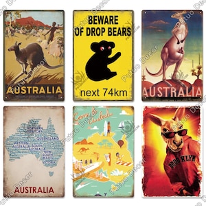 Puede incluir: Una colección de letreros metálicos de estilo vintage con temas australianos. Los letreros representan canguros, mapas y advertencias. La paleta de colores incluye tonos de marrón, amarillo y rojo, con texto como "Australia" y "Beware of Drop Bears".