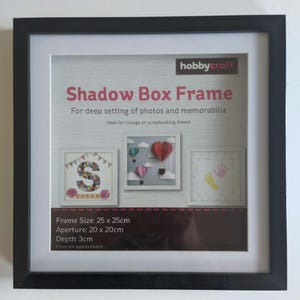 May include: Black shadow box frame with a white mount and a white background. The frame is labelled "Shadow Box Frame" and has the text "For deep setting of photos and memorabilia" and "Ideal for collage or scrapbooking sheets". The frame size is 25cm by 25cm, the aperture is 20cm by 20cm, and the depth is 3cm.