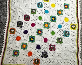 May include: White crochet baby blanket with a colorful owl design. The blanket features a variety of colors, including red, yellow, green, blue, and purple. The owls are crocheted in a variety of colors and have black eyes.