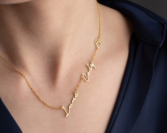 May include: A gold necklace with a paw print charm and the names "Luna" and "Vada" written in cursive.