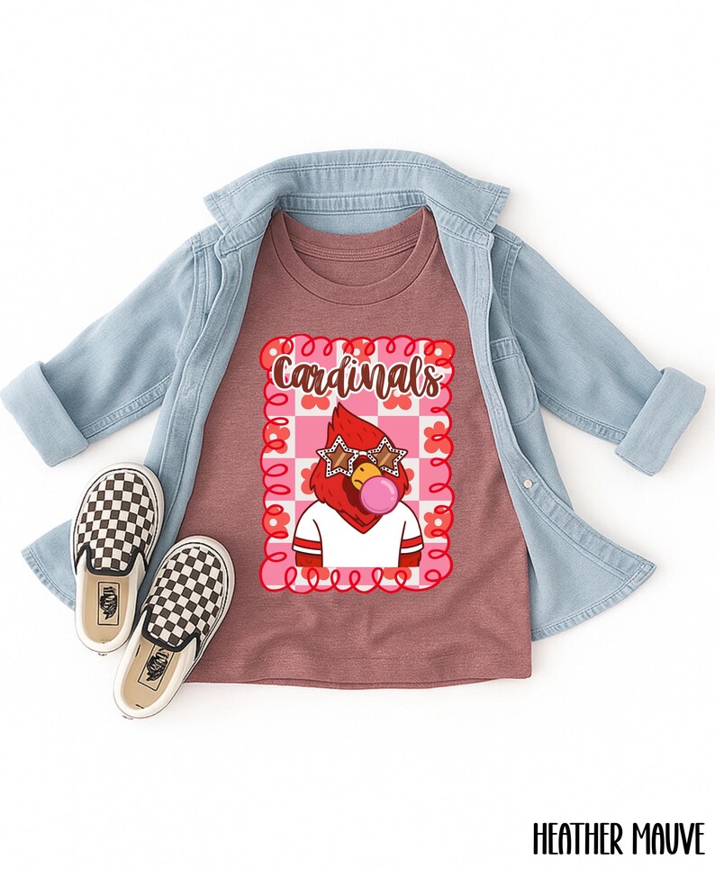 heather mauve t-shirt featuring a cartoon cardinal with star-shaped sunglasses blowing a bubble. The cardinal is wearing a white shirt with red stripes. The word "Cardinals" is written in brown script within a pink and red floral frame.