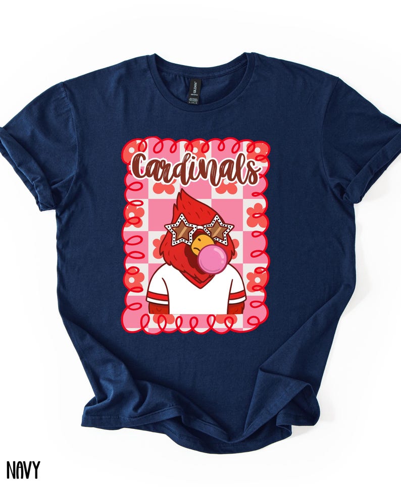 Navy blue t-shirt featuring a cartoon cardinal wearing star-shaped sunglasses and blowing a bubblegum bubble. The graphic is set within a pink and white checkered frame with the word "Cardinals" in a script font.