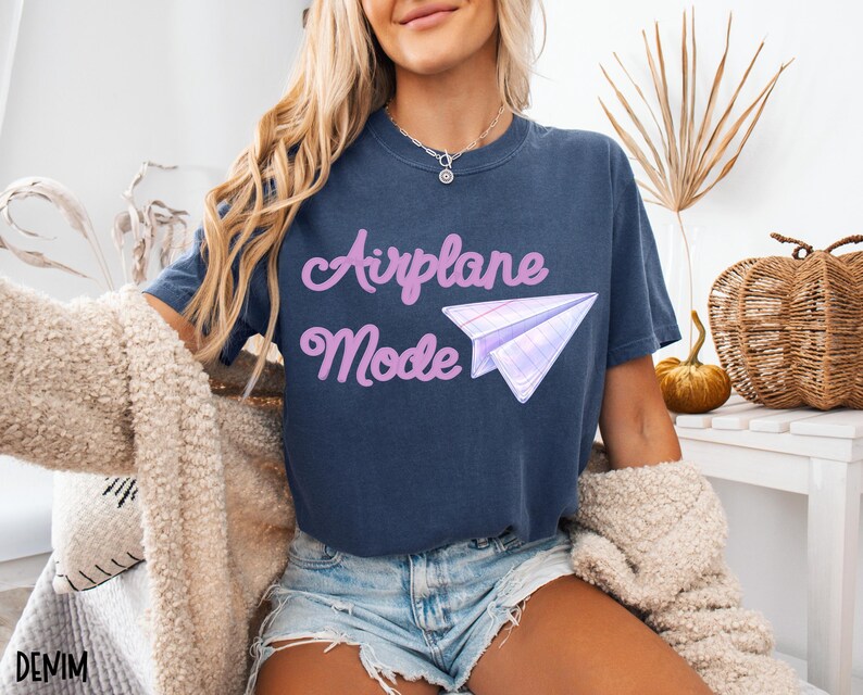 Navy blue t-shirt with the text "Airplane Mode" in a cursive font and a paper airplane graphic. The shirt is made of a soft material and is suitable for casual wear. The word "DENIM" is printed at the bottom left.
