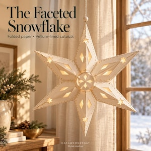 May include: A hanging star-shaped ornament made of folded paper with vellum-lined cutouts. The off-white structure features gold-speckled edges and star-shaped perforations. Text reads: The Faceted Snowflake, Folded paper, Vellum-lined cutouts.