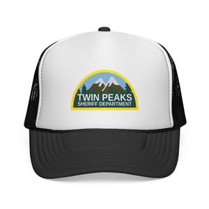 Puede incluir: Gorra de camionero en blanco y negro con un panel frontal blanco con el logotipo "Twin Peaks Sheriff Department". El logotipo incluye una cordillera, árboles y texto en un diseño amarillo y azul.
