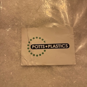 May include: A clear plastic bag filled with white plastic pellets. The bag has a white label with the text "POTTS PLASTICS" in black.