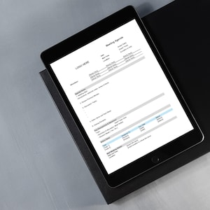 May include: A black tablet displaying a "Meeting Agenda" document, resting on a black surface. The document includes sections for date, time, location, and agenda items. The tablet is on a gray surface.
