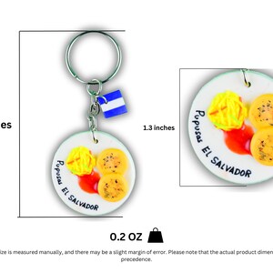K&ouml;nnte beinhalten: Ein wei&szlig;er Keramik-Schl&uuml;sselanh&auml;nger mit einem gelben und braunen 3D-Bild von Pupusas, einem traditionellen salvadorianischen Gericht, mit dem Text "Pupusas El Salvador". Der Schl&uuml;sselanh&auml;nger ist 8,4 cm hoch und 3,3 cm breit.