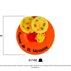 Puede incluir: Un plato de cer&aacute;mica naranja de 5 cm de di&aacute;metro con un borde blanco, que representa dos pupusas, un acompa&ntilde;amiento de curtido y una salsa roja. El plato est&aacute; decorado con el texto "Pupusas de El Salvador".