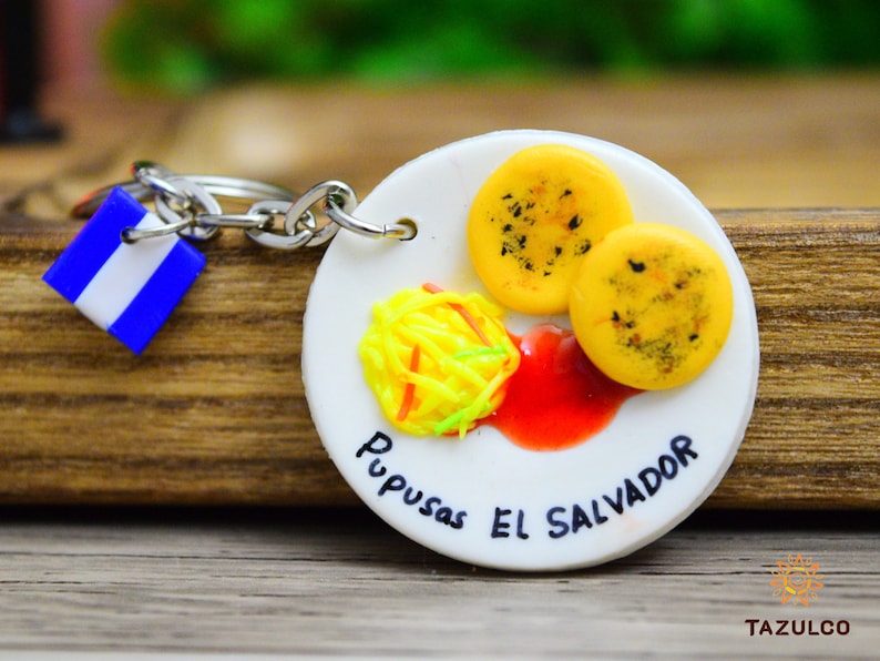 🫓🔥 **Llavero de Pupusas – Tradición Salvadoreña** 🇸🇻  

Lleva contigo el sabor de **El Salvador** con este **llavero artesanal de pupusas**, elaborado en **porcelana fría** con detalles realistas. Su diseño recrea el dorado perfecto de una pupusa recién salida de la **plancha**, capturando su esencia única. **Duradero, resistente y perfecto para coleccionistas y amantes de la comida típica.** Un símbolo de orgullo salvadoreño que te conecta con tus raíces.
