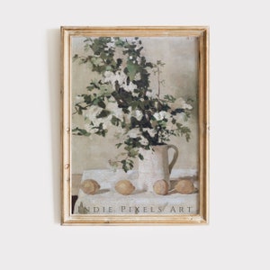 Puede incluir: Una pintura enmarcada de una jarra blanca llena de flores blancas y limones sobre un mantel blanco. La pintura está en un marco de madera claro.
