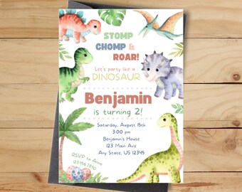 May include: Watercolor dinosaur-themed birthday party invitation. The invitation features illustrations of various dinosaurs, tropical leaves, and the text "STOMP, CHOMP & ROAR!" and "Benjamin is turning 2!" on a white background. The invitation is on a wooden surface.