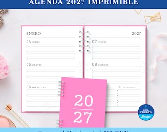 May include: A spiral-bound 2027 planner with a bright pink cover and white interior pages. The open pages display a weekly layout for January with the days of the week in Spanish, including Lunes, Martes, Miércoles, Jueves, Viernes, and Domingo.