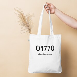 May include: White tote bag with black text that reads "01770 sherborn, ma".